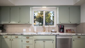 A kitchen with light green cabinets, a double sink, and a dishwasher. - Charming vacation rental steps away from River Island Golf Course (Porterville)