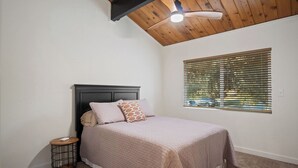 A bedroom with a bed, a ceiling fan, a window with blinds, and a small bedside table. - Charming vacation rental steps away from River Island Golf Course (Porterville)