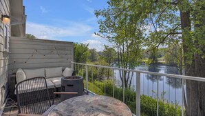 Un balcon avec une table en pierre, des sièges d’extérieur et une vue sur un lac.