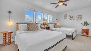 A bedroom with two beds, a ceiling fan, and large windows.