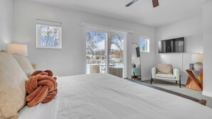 Une chambre moderne avec un grand lit, un coin salon comprenant une chaise et une table, et un téléviseur fixé au mur.