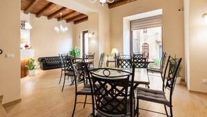 Un comedor con una mesa redonda y sillas, vigas de madera en el techo y una araña.