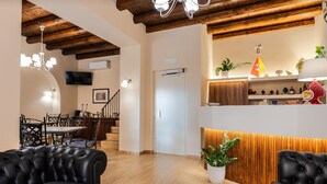 Un interior moderno con comedor, dos sofás de cuero negro, piso de madera, una escalera y una cocina con paneles de madera.