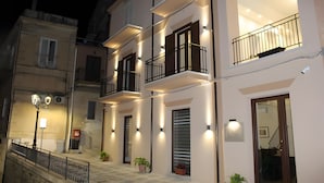Un immeuble à plusieurs étages doté de balcons, d’un éclairage extérieur et d’un escalier menant à l’entrée.