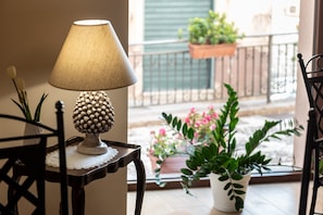 A table with a lamp, a potted plant, and a lace doily.