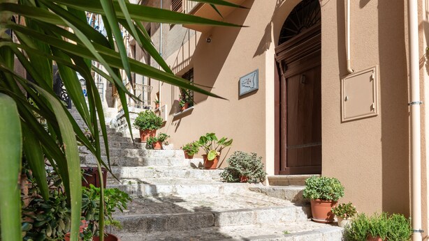 A stone staircase leading to a building with multiple potted plants and a wooden door. - Deluxe Triple Room with Balcony, Wi-Fi and Air Conditioning (Caccamo)