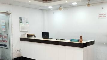 Un mostrador de recepción de hotel con una decoración en blanco y negro, un calendario en la pared y un cartel de 'No Fumar'.