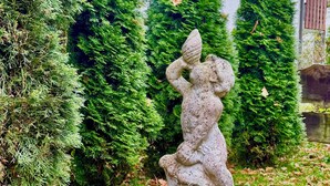 A garden with a stone sculpture of a woman and child, surrounded by evergreen trees and fallen leaves. - Cozy and quiet garden vacation apartment in the heart of Dießen am Ammersee (Dießen am Ammersee)