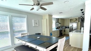 Una cucina moderna con isola centrale, zona pranzo con tavolo e sedie e ventilatore a soffitto.