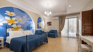 Een slaapkamer met een bed, een blauwe bank, een bureau en een stoel.