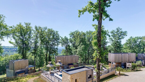 A modern outdoor cabin with a pool, surrounded by trees and a clear view of the landscape.