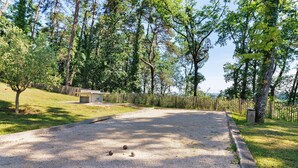 Un vialetto sterrato con tre bocce, circondato da alberi e un recinto in legno.