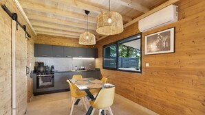 Une cuisine moderne avec des murs en bois, une table à manger entourée de chaises jaunes et des luminaires suspendus.