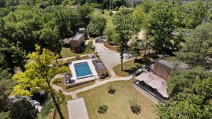 Vue aérienne d’une propriété comprenant une piscine, plusieurs bâtiments et un espace vert environnant.