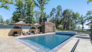 A swimming pool with lounge chairs and a wooden structure with a thatched roof. - Le Pech Eternel – Master Bedroom La Noyeraie (Sarlat la Canéda)