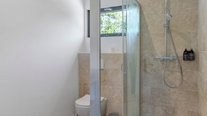 A modern bathroom with a glass shower enclosure, a toilet, and a small trash bin. - Le Pech Eternel – Master Bedroom La Noyeraie (Sarlat la Canéda)