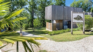A modern wooden cabin with a gravel path, surrounded by lush greenery and trees. - Le Pech Eternel – Master Bedroom La Noyeraie (Sarlat la Canéda)