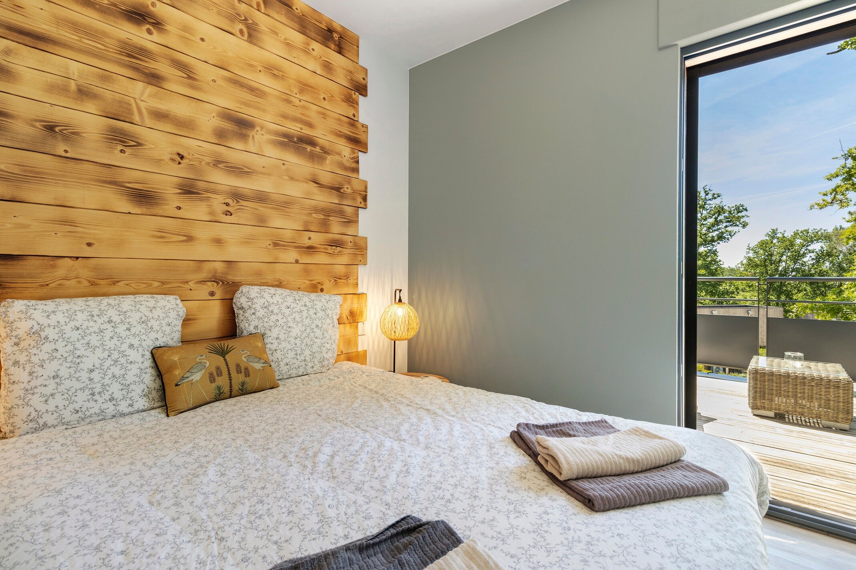 Una camera da letto con una testiera in legno, biancheria da letto floreale, una lampada da comodino e vista all'esterno.