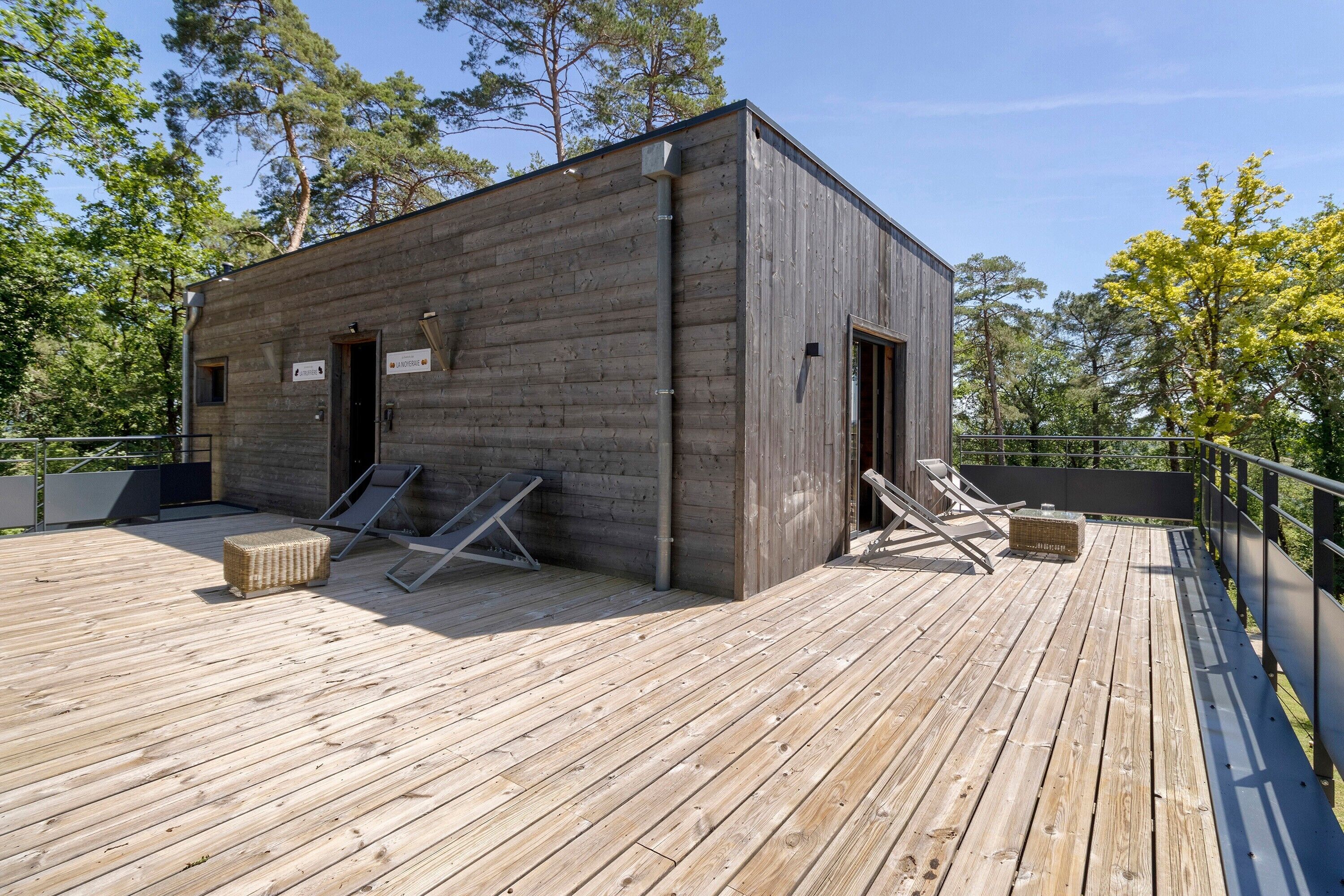 A wooden cabin with a deck, two doors, and a small window.