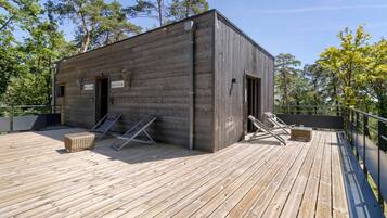 A wooden cabin with a deck, two doors, and a small window.