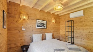A wooden-paneled room with a bed, a small table, a wall-mounted shelf, and a hanging light fixture. - Le Pech Eternel - Lodge Spa Acacias (Sarlat la Canéda)
