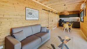 A modern interior with a sofa, dining table, and kitchen area. - Le Pech Eternel - Lodge Spa Acacias (Sarlat la Canéda)