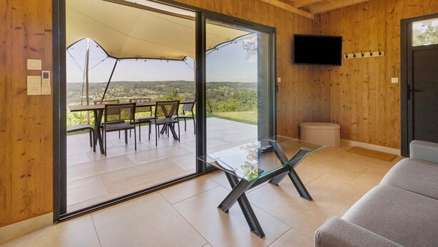A modern interior with a glass table, a sofa, and a television on the wall.
