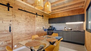 A modern kitchen with a dining area featuring a glass table and yellow chairs.