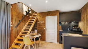Eine moderne Küche mit Holzelementen, ein Essbereich mit Tisch und Stühlen sowie eine Holztreppe.