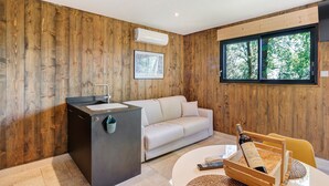 Ein modernes Zimmer mit Holzwänden, einer Couch, einer kleinen Küchenzeile und einem großen Fenster.