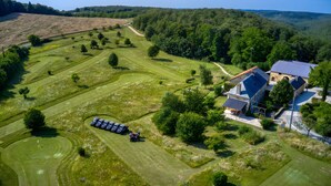 An aerial view of a golf course with a building that has a blue roof and a stone facade. - Holiday Home 'Les Crouquets - La Grange' with Shared Terrace, Private Garden and Wi-Fi (Jayac)