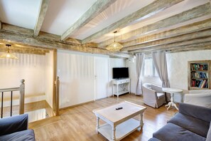 Un salon avec un plafond en bois, une télévision, un canapé, une table basse et une bibliothèque.
