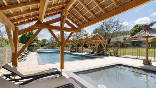 A swimming pool with lounge chairs, a wooden pergola, and a thatched-roof structure. - Les Crouquets - Le Fournil (Jayac)