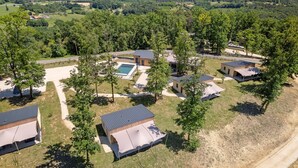 An aerial view of a resort with multiple cabins, a swimming pool, and a clear view of the surrounding landscape.