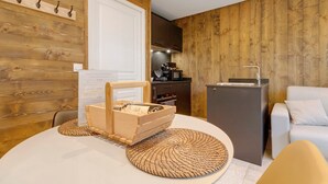 A modern kitchen with wooden walls, a white dining table, and a compact refrigerator.