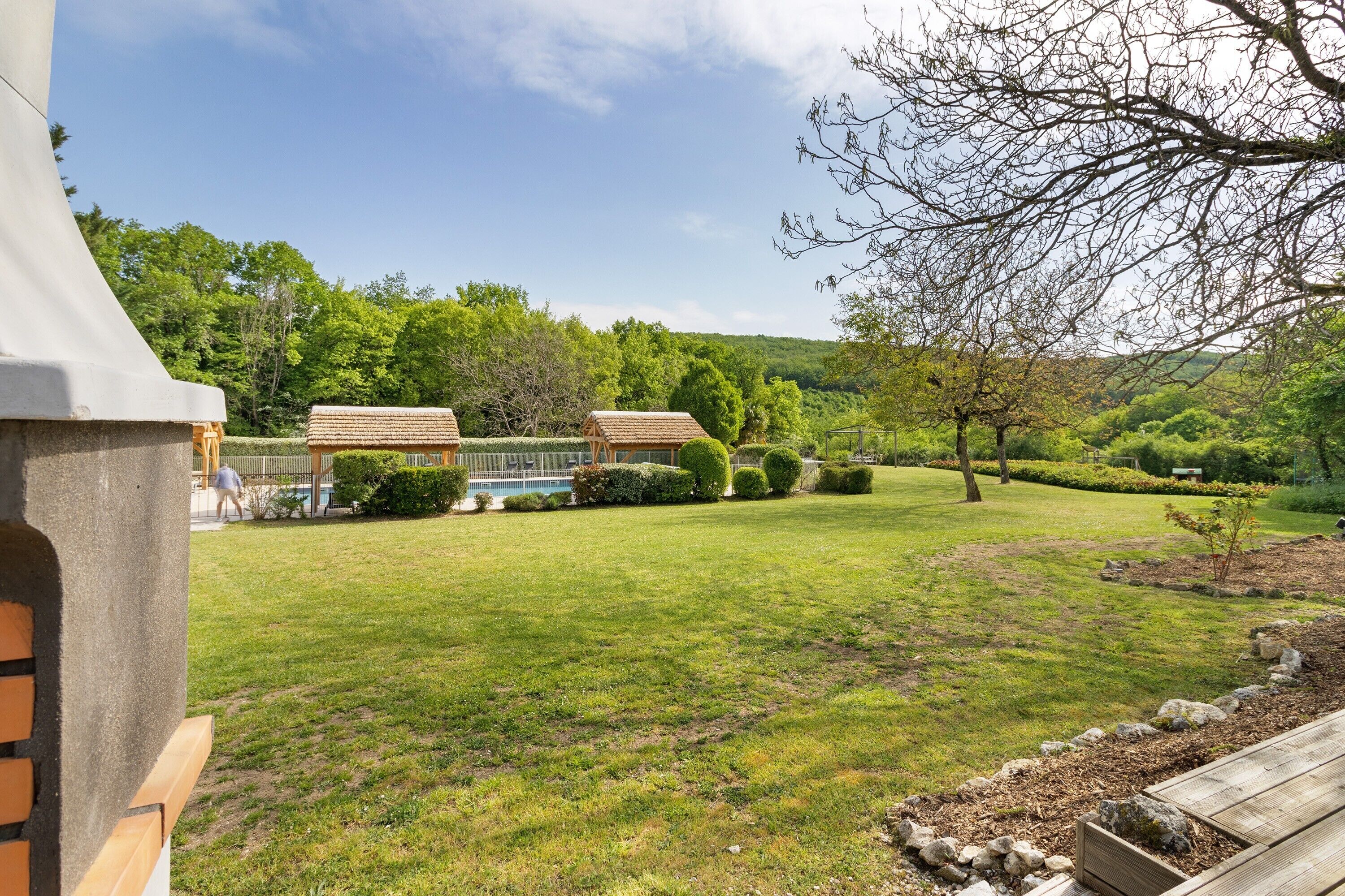 A well-maintained garden with a wooden deck, a gazebo, and a swimming pool.