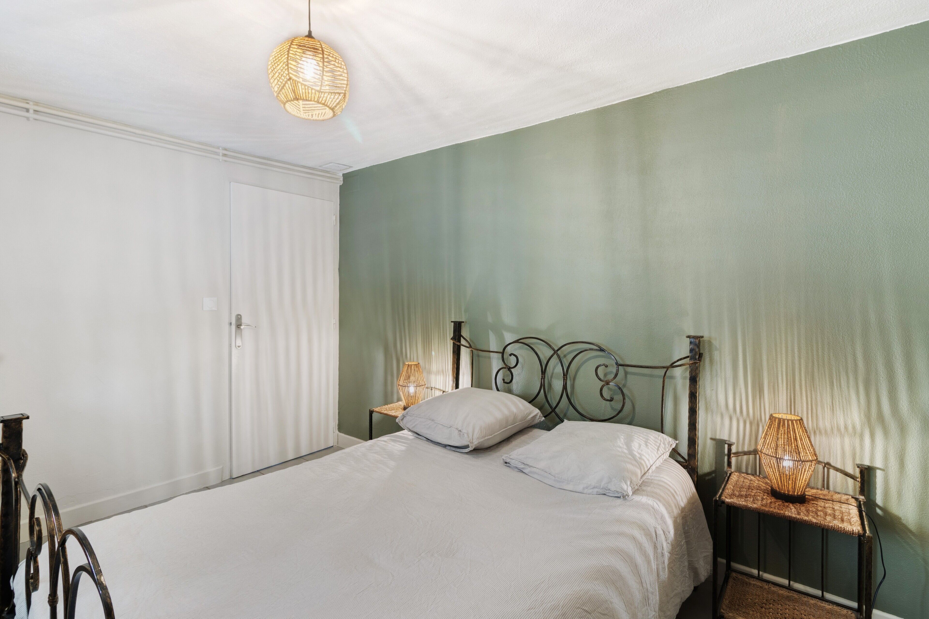Une chambre à coucher avec un lit, des lampes de chevet, une porte et un luminaire suspendu.