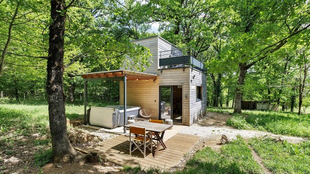 Une cabane moderne dotée d’une terrasse, d’un espace salon extérieur et d’un bain à remous.