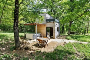 Une cabane moderne dotée d’une terrasse, d’un espace salon extérieur et d’un bain à remous.