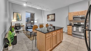 Una cocina moderna con armarios de madera, una isla central, electrodomésticos de acero inoxidable y una zona de comedor con mesa y sillas.