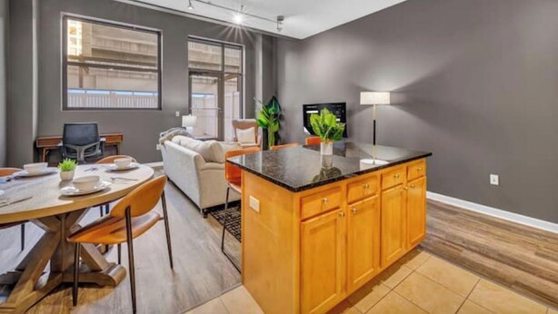 A modern kitchen with a central island, wooden cabinets, and a dining area with a table and chairs.