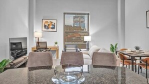 Ein modernes Wohnzimmer mit Essbereich, Fernseher und Blick auf die Stadt.