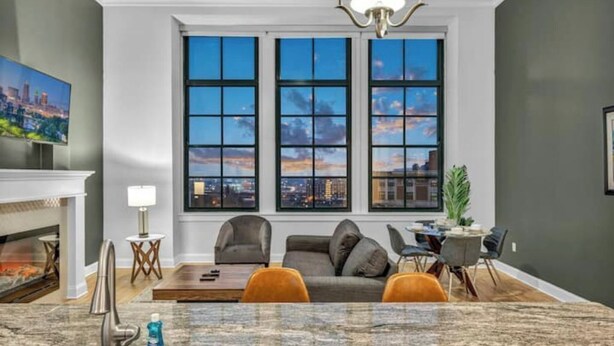 Ein modernes Wohnzimmer mit Kamin, großem Fenster und Stadtblick, Essbereich und Küchenzeile.
