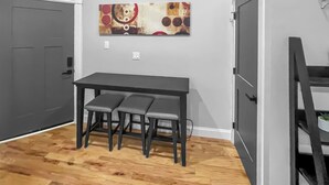 A room with a dining table and chairs, a gray door, and a wall-mounted artwork. - Exquisite 1st Floor One Bedroom in Historic Marble Hill w/ Modern Amenities (Baltimore)