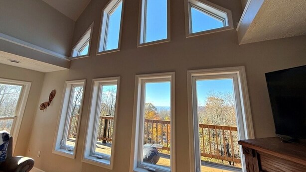 A room with multiple windows, a wooden deck, and a television. - Spacious 4-bedroom + loft, 8 Min Drive to Resort, Equipped Hot Tub & Activities (Cass)