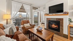 Una sala de estar moderna con chimenea, asientos confortables, televisor de pantalla plana y un balcón con vistas panorámicas.