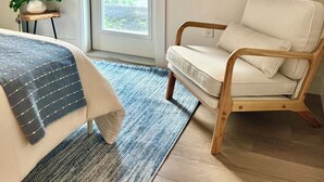 Una camera da letto con un letto, una sedia, una TV e una porta che dà su un balcone.