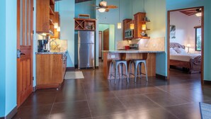 A spacious kitchen with wooden cabinets, a central island with stools, a refrigerator, and a microwave. - Breathtaking views on the pacific ocean - inifnity edge pool (Dominicalito)