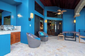 Un patio exterior con mobiliario de mimbre, una parrilla y una mesa de comedor.
