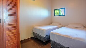 A room with two beds, a wooden wardrobe, and an air conditioning unit. - Breathtaking views on the pacific ocean - inifnity edge pool (Dominicalito)